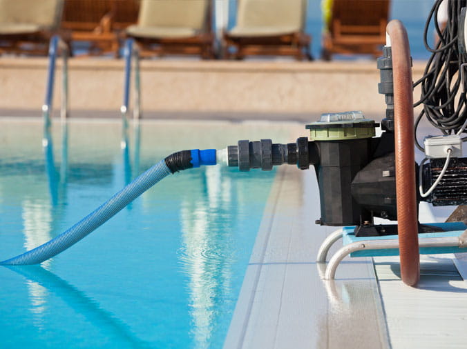 Pool vaccum on the side of a private backyard swimming pool